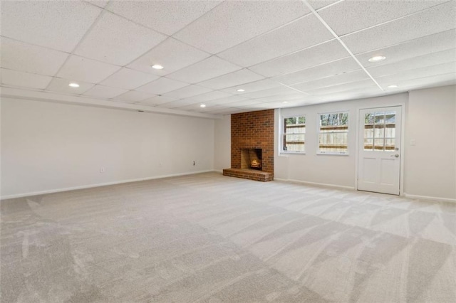 unfurnished living room featuring a brick fireplace, baseboards, and carpet