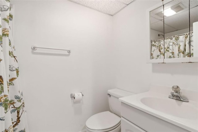 bathroom with vanity, a shower with shower curtain, toilet, and a paneled ceiling