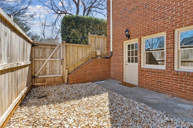 exterior space featuring a gate, fence, and brick siding