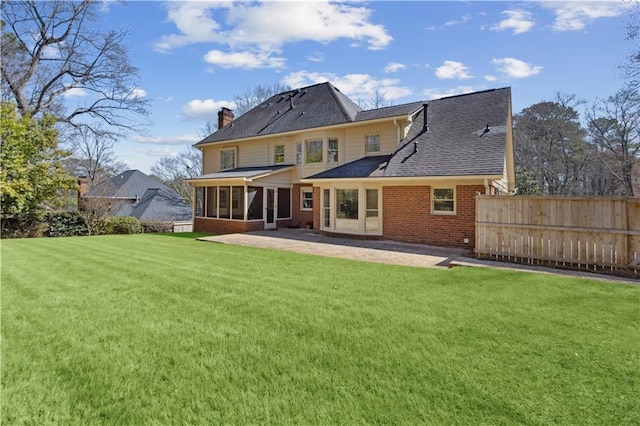 back of house with fence, a yard, a sunroom, a chimney, and a patio area