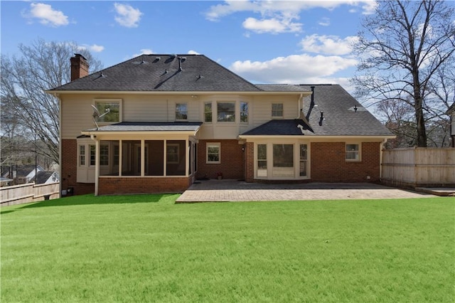 back of property with a yard, brick siding, a patio, and a sunroom