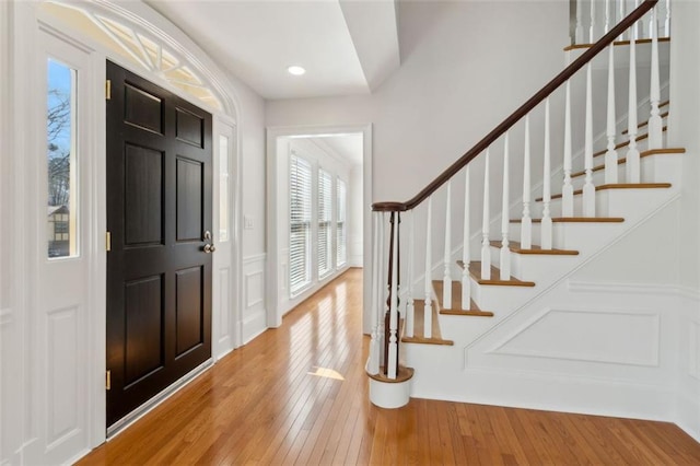 foyer entrance with stairway, a decorative wall, and light wood-type flooring