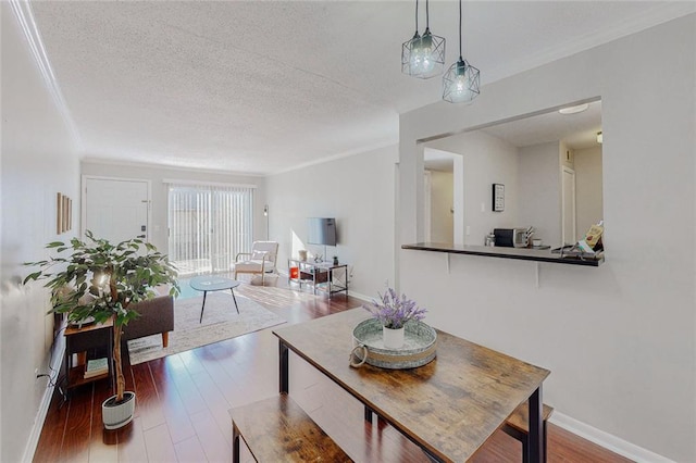 dining room with hardwood / wood-style flooring, ornamental molding, and a textured ceiling