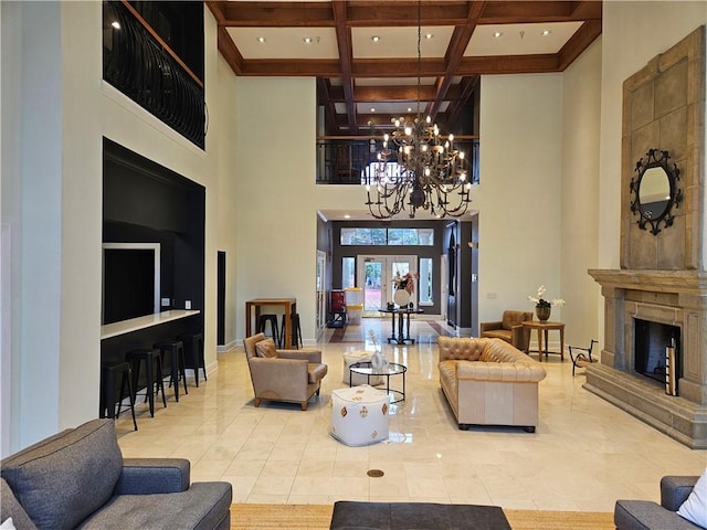 living room with a fireplace, a chandelier, a high ceiling, coffered ceiling, and french doors