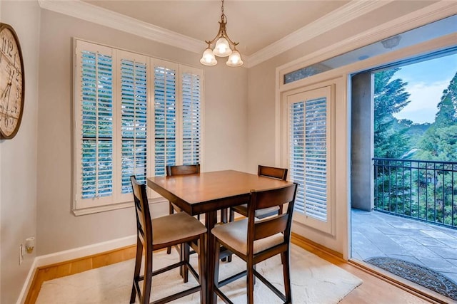 dining area with ornamental molding, light hardwood / wood-style floors, and a notable chandelier