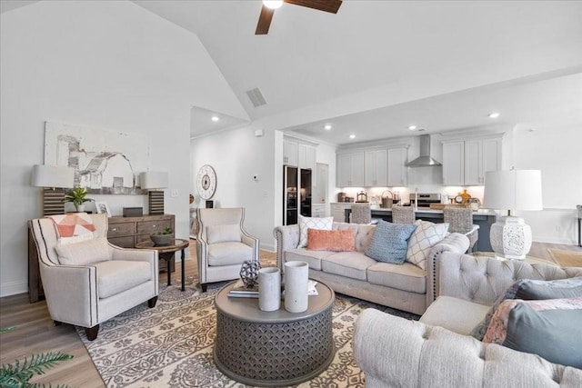 living room with high vaulted ceiling, ceiling fan, and light hardwood / wood-style flooring