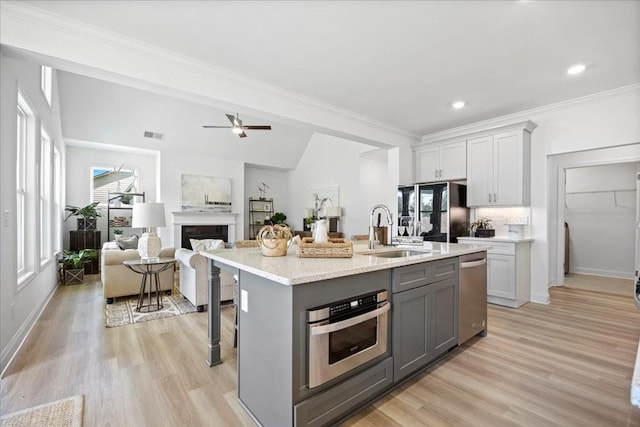 kitchen with a center island with sink, appliances with stainless steel finishes, gray cabinetry, a breakfast bar, and sink