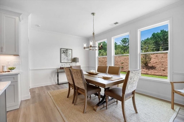 dining area featuring a notable chandelier, light hardwood / wood-style flooring, and ornamental molding