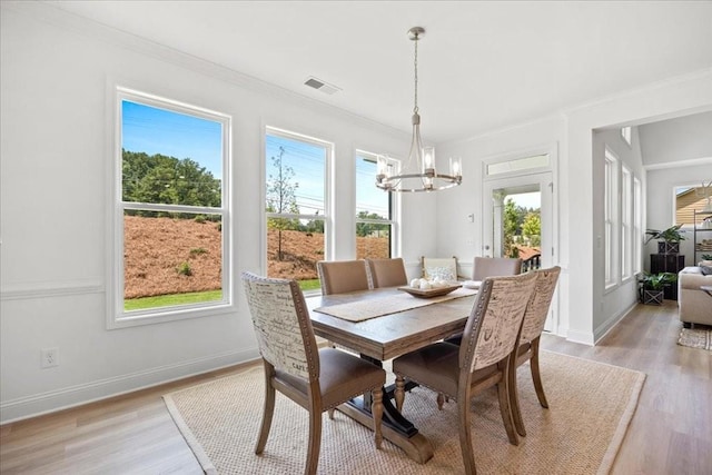 dining area featuring ornamental molding, a chandelier, and light hardwood / wood-style flooring