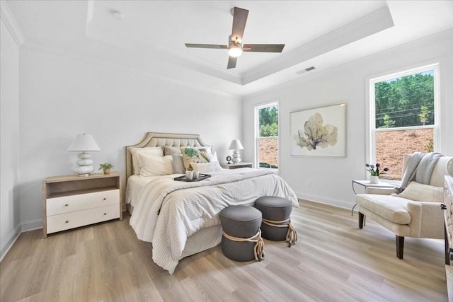 bedroom with a tray ceiling, ornamental molding, and light hardwood / wood-style floors