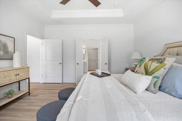 bedroom with a tray ceiling, light hardwood / wood-style floors, and crown molding