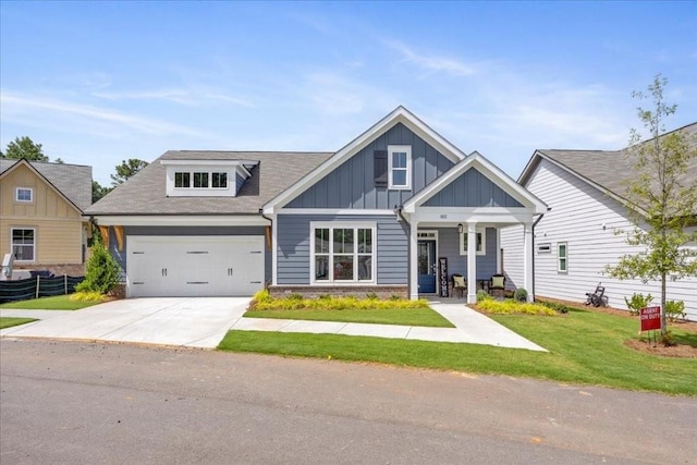 craftsman inspired home with covered porch, a front yard, and a garage