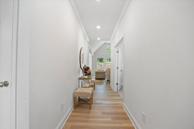 hall with light hardwood / wood-style floors, crown molding, and lofted ceiling