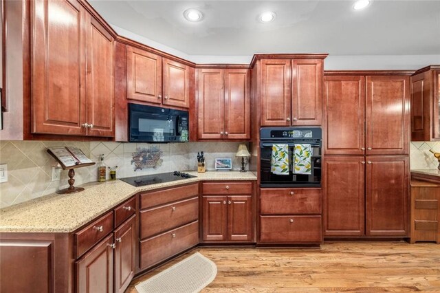 kitchen featuring black appliances, backsplash, light wood finished floors, light stone countertops, and recessed lighting