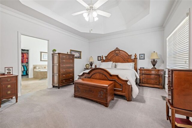 bedroom with a raised ceiling, light carpet, crown molding, ceiling fan, and connected bathroom