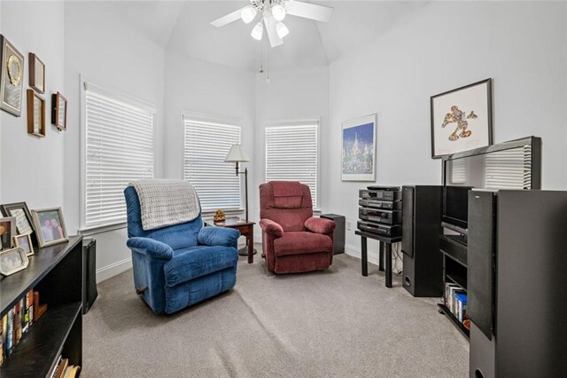 living area featuring carpet floors, ceiling fan, a high ceiling, baseboards, and healthy amount of natural light