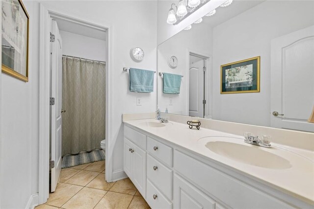 full bath with toilet, tile patterned floors, and double vanity