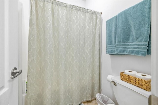 full bathroom with toilet and tile patterned flooring