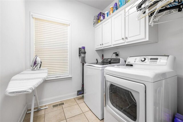 washroom with washing machine and dryer, cabinet space, baseboards, and light tile patterned floors