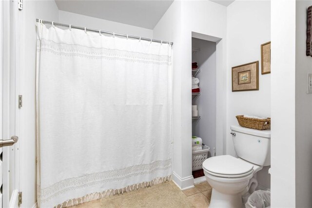 bathroom with toilet, baseboards, and tile patterned floors