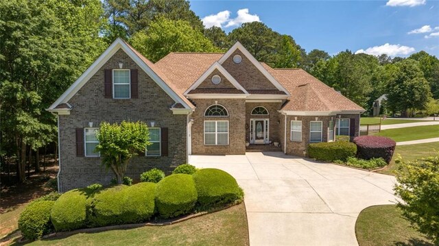 view of front facade featuring brick siding, a front lawn, and driveway