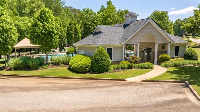 view of front of home featuring a gazebo, a shingled roof, fence, and an outdoor pool