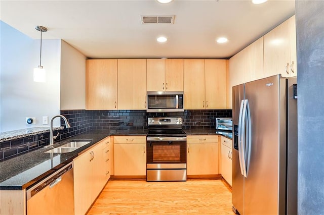 kitchen featuring appliances with stainless steel finishes, decorative light fixtures, sink, and light brown cabinets