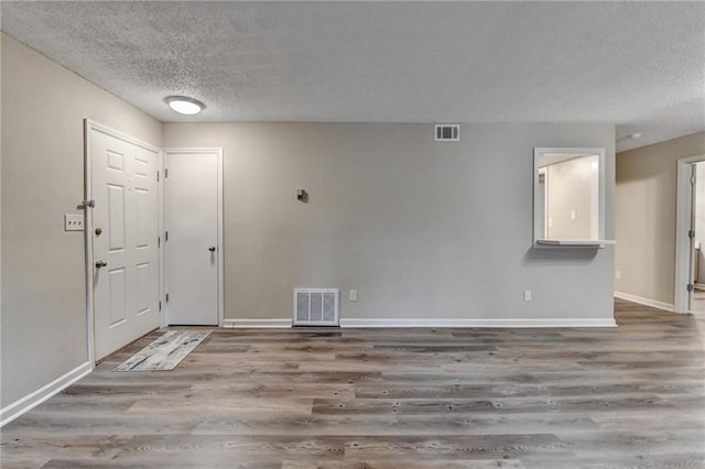 unfurnished room featuring visible vents, baseboards, wood finished floors, and a textured ceiling