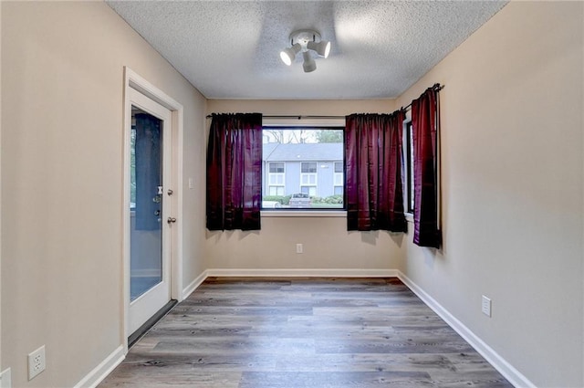 empty room featuring baseboards, wood finished floors, and a textured ceiling