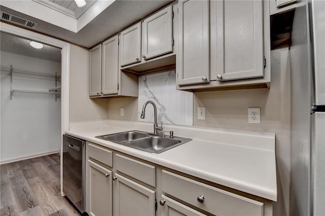 kitchen with visible vents, wood finished floors, dishwasher, light countertops, and a sink