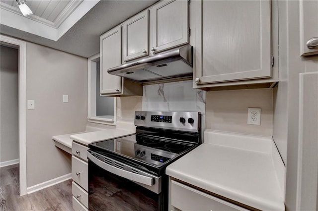 kitchen with baseboards, light countertops, stainless steel range with electric stovetop, under cabinet range hood, and light wood finished floors