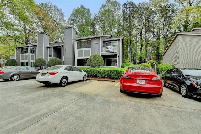 view of front facade featuring uncovered parking and a chimney