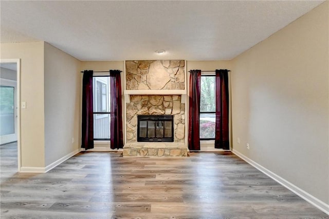 unfurnished living room featuring wood finished floors, a fireplace, and baseboards
