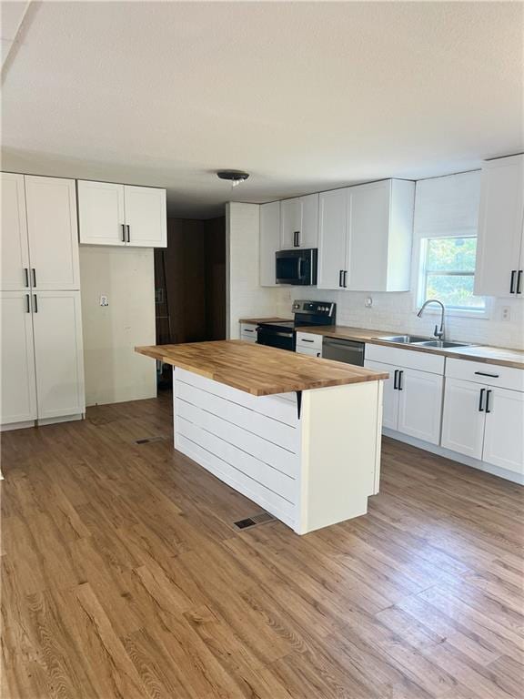 kitchen with wood counters, sink, white cabinets, light wood-type flooring, and appliances with stainless steel finishes