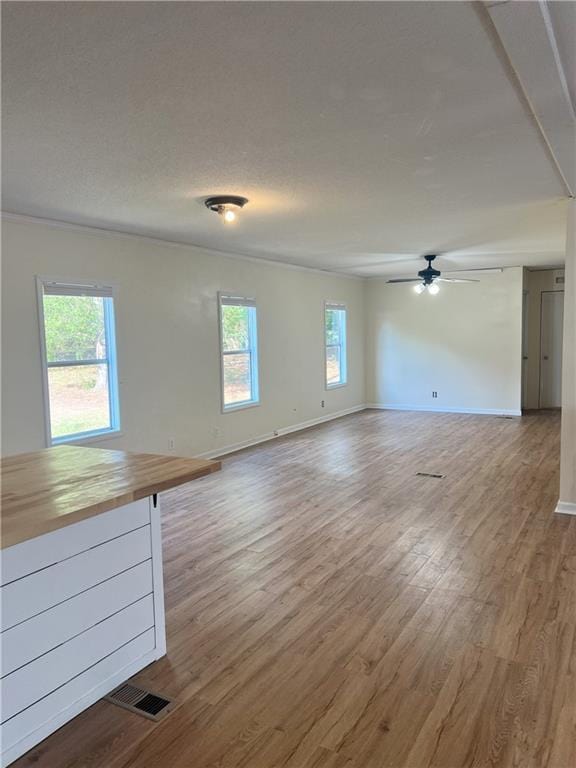 unfurnished living room featuring ceiling fan, a healthy amount of sunlight, and hardwood / wood-style floors