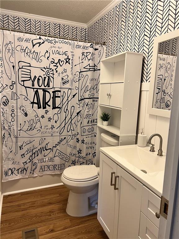 full bathroom featuring hardwood / wood-style floors, a textured ceiling, toilet, vanity, and crown molding