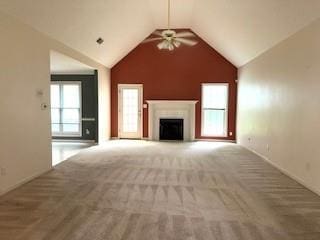 unfurnished living room with a ceiling fan, vaulted ceiling, a fireplace, carpet, and baseboards