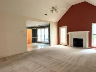 unfurnished living room with carpet flooring, healthy amount of natural light, high vaulted ceiling, and a fireplace