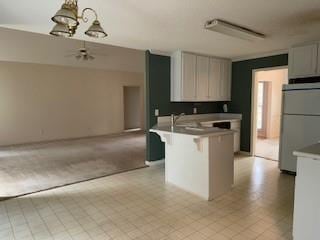 kitchen featuring fridge, open floor plan, a kitchen breakfast bar, a peninsula, and decorative light fixtures
