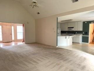 unfurnished living room featuring high vaulted ceiling and light carpet
