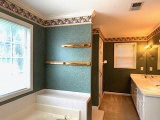full bath featuring a garden tub, vanity, and ornamental molding