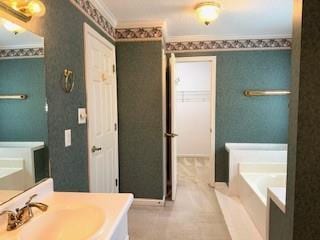 full bath with crown molding, a garden tub, baseboards, and vanity