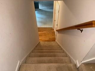 stairs with wood finished floors and baseboards