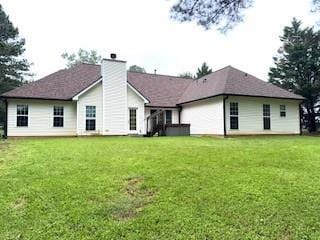 back of house with a chimney and a lawn