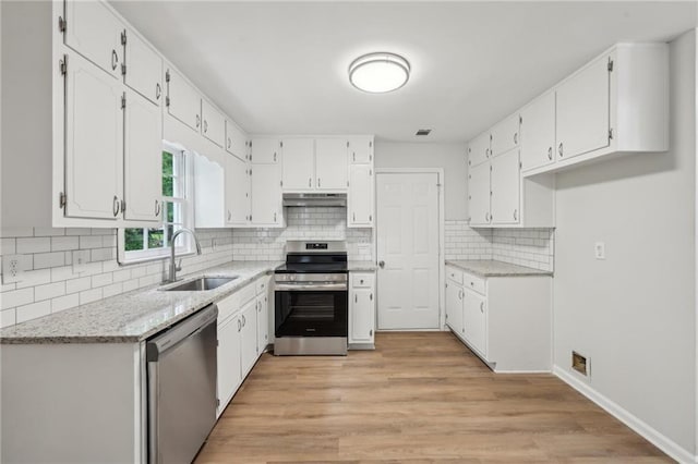 kitchen with under cabinet range hood, stainless steel appliances, white cabinetry, and a sink