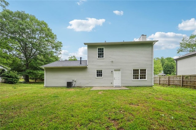 back of house featuring a chimney, fence, central AC, a patio area, and a lawn