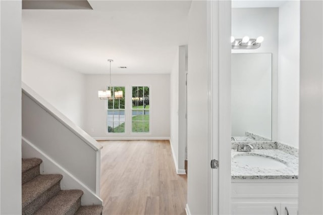 interior space featuring a chandelier, wood finished floors, and baseboards
