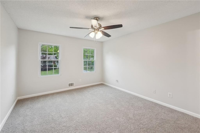 carpeted spare room with ceiling fan, baseboards, a textured ceiling, and visible vents