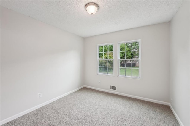carpeted spare room with baseboards, visible vents, and a textured ceiling