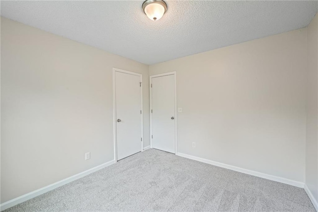 carpeted empty room featuring baseboards and a textured ceiling